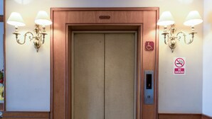 Een lift met een rookverbodsge teken, een rolstoeltoegankelijkheidsge teken en een brandveiligheidsge teken.