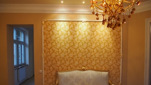 Una stanza con una grande poltrona decorata, carta da parati a fantasia e un lampadario.