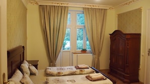 Una camera da letto con due letti, un armadio in legno e una finestra con tende.