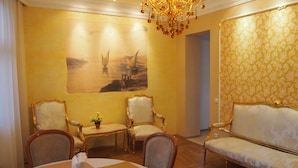Zona pranzo con tavolo apparecchiato per due, due sedie decorate, un divano e un lampadario.