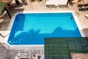 Una piscina rectangular con agua cristalina, rodeada por una solana con baldosas y sillas de descanso.