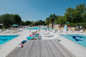 A pool area with multiple swimming pools, lounge chairs, and umbrellas. - Camping Sabbiadoro (Lignano Sabbiadoro)