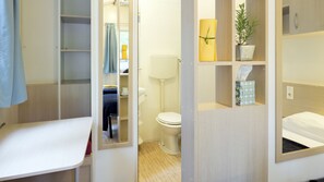 A compact hotel room with a bed, a small desk, a bathroom with a toilet and sink, and a mirror. - Camping Sabbiadoro (Lignano Sabbiadoro)