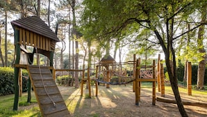 Un parque infantil con estructuras de madera, como un tobogán y una red para escalar.