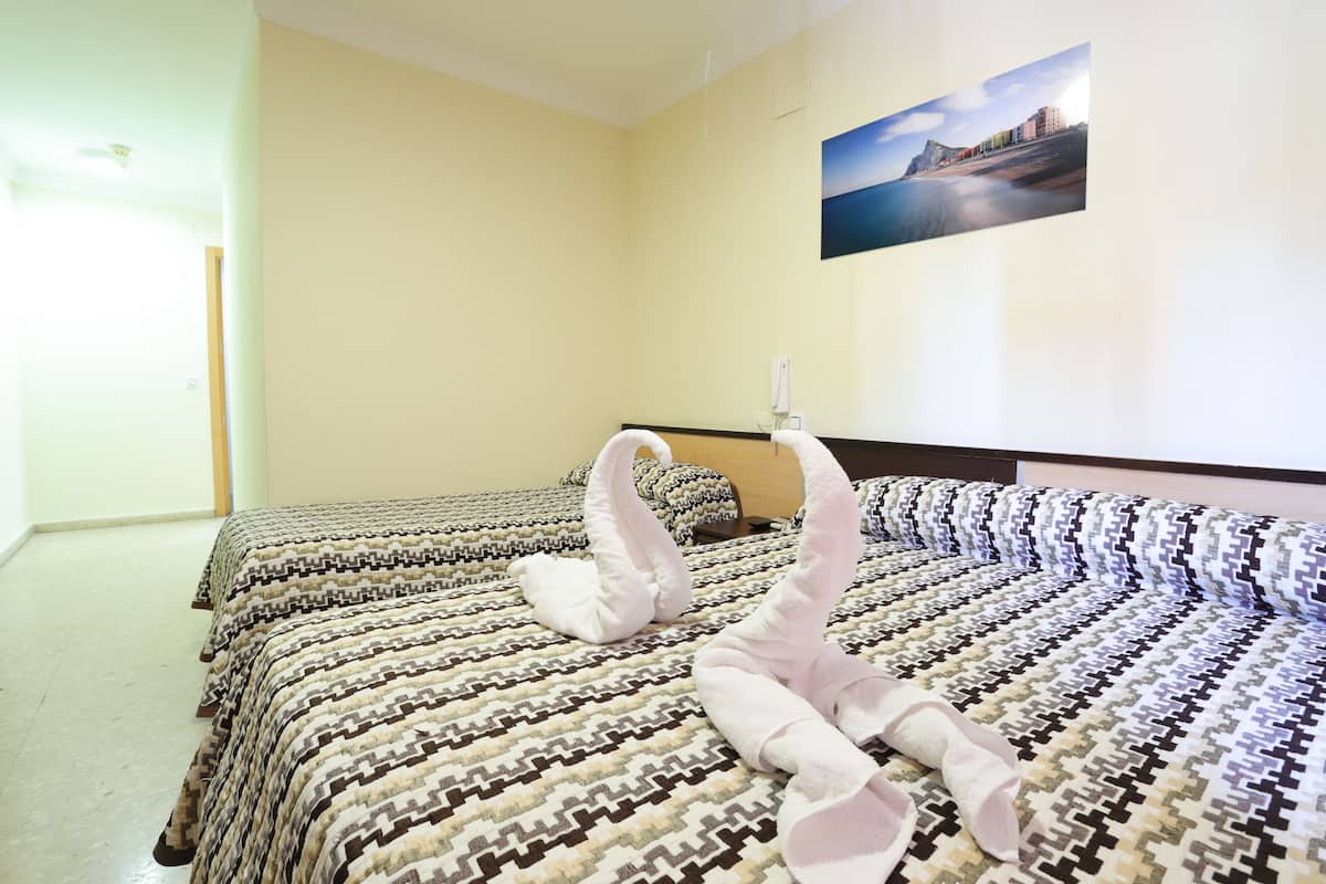 Una habitación de hotel con dos camas, un cuadro colgado en la pared y una puerta.