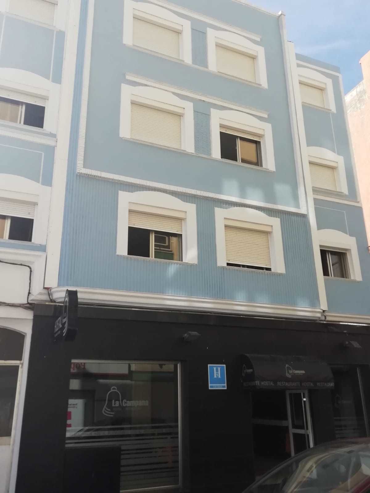A multi-story hotel with a blue and white facade, a visible entrance, and a sign indicating it is a hotel.