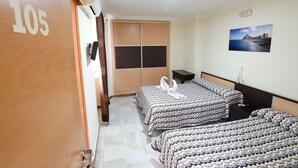 Une chambre d’hôtel avec deux lits, une armoire, une table de chevet et un tableau accroché au mur.
