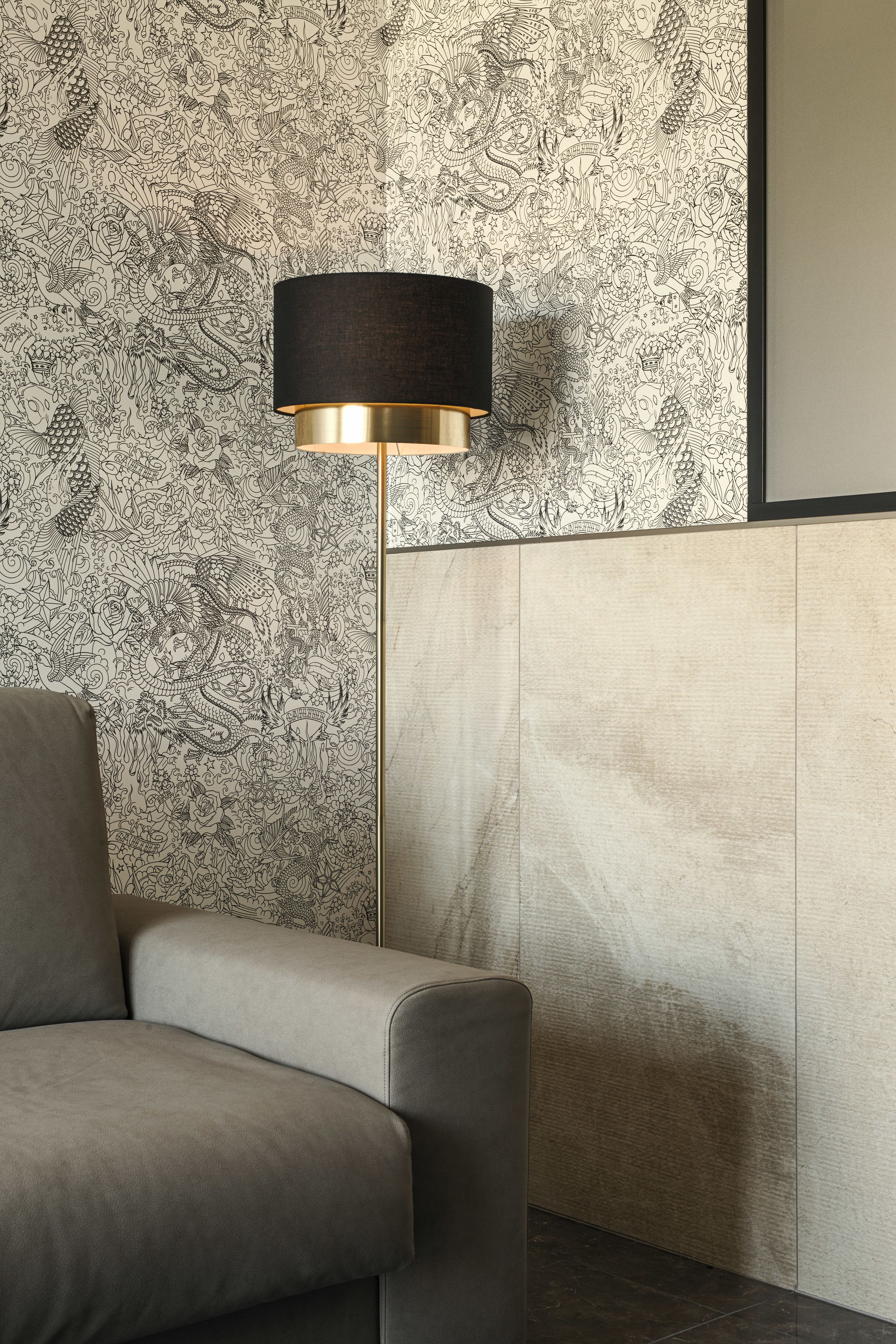 Habitació moderna amb paper pintat estampat, una làmpada de peu i un sofà.