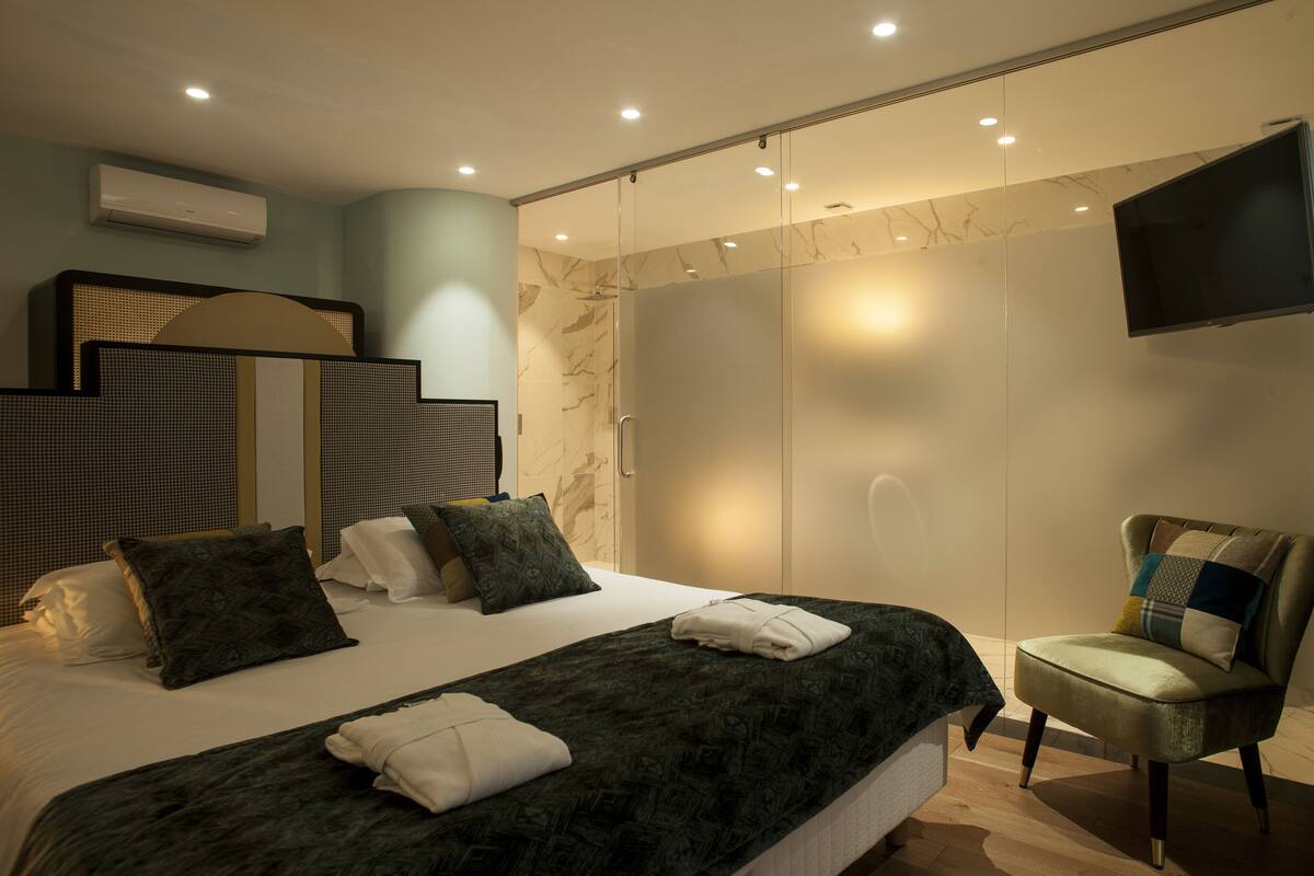 Une chambre moderne avec un grand lit, une chaise, une armoire et un téléviseur.