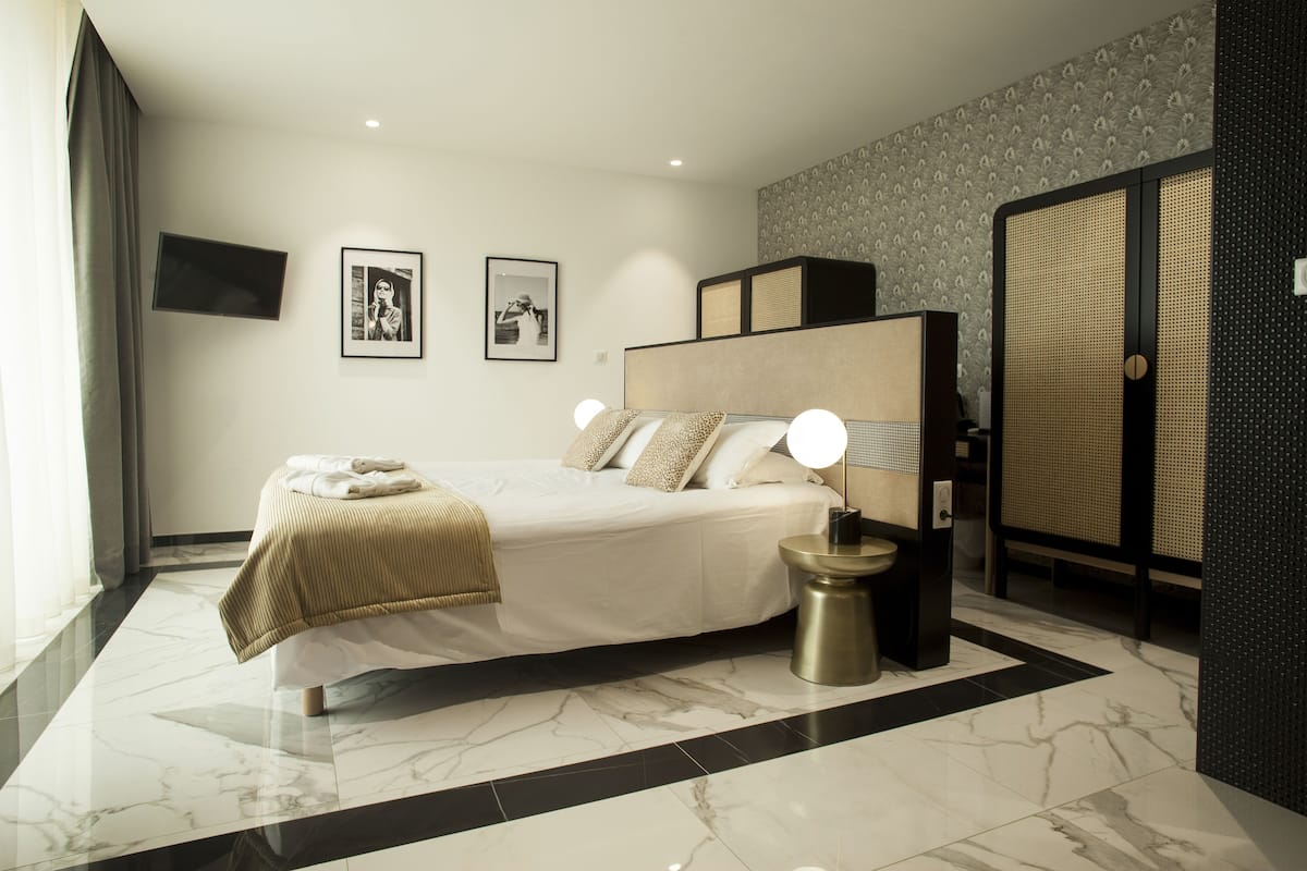 Une chambre d’hôtel moderne avec un grand lit, des lampes de chevet, une petite table et une armoire.