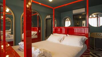 A hotel room with a large bed, red accents, and multiple mirrors.