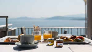 Una mesa de desayuno con croissants, una taza, un vaso de zumo de naranja y un plato de comida, con vistas a un paisaje pintoresco.