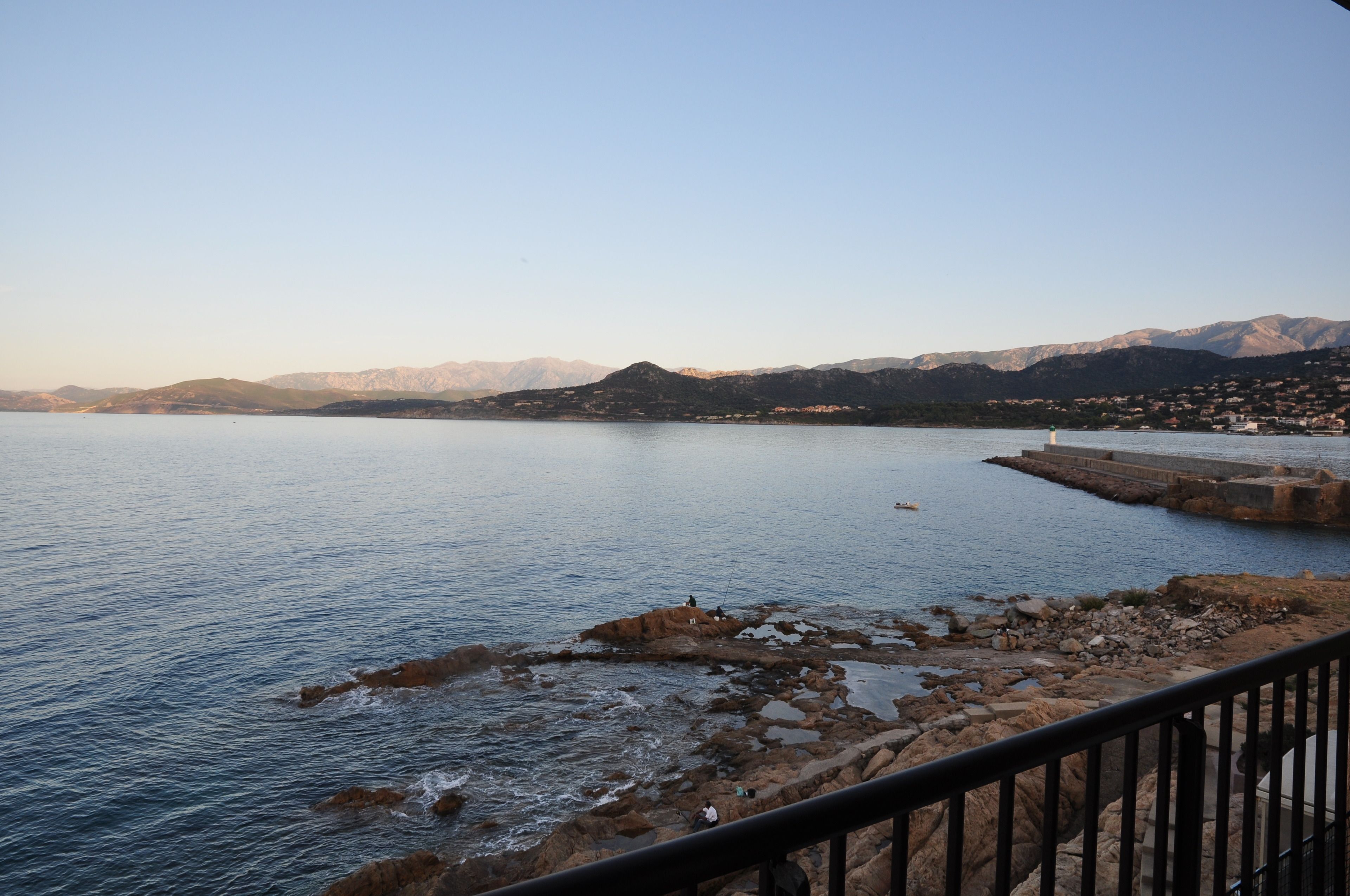 A coastal view with rocky terrain and a distant town.