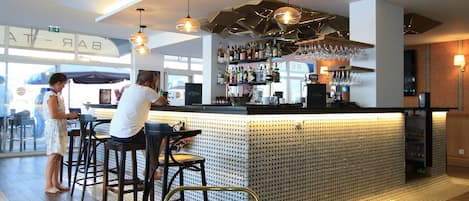 Un bar moderno con una barra alta, taburetes y un área de estar con un tapiz estampado.