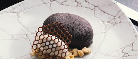 A dessert on a cracked white plate with a honeycomb structure and crumbs, accompanied by a fork.