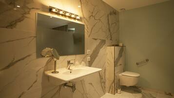 Une salle de bain avec un lavabo en marbre, un miroir avec éclairage intégré, des toilettes et un espace douche.