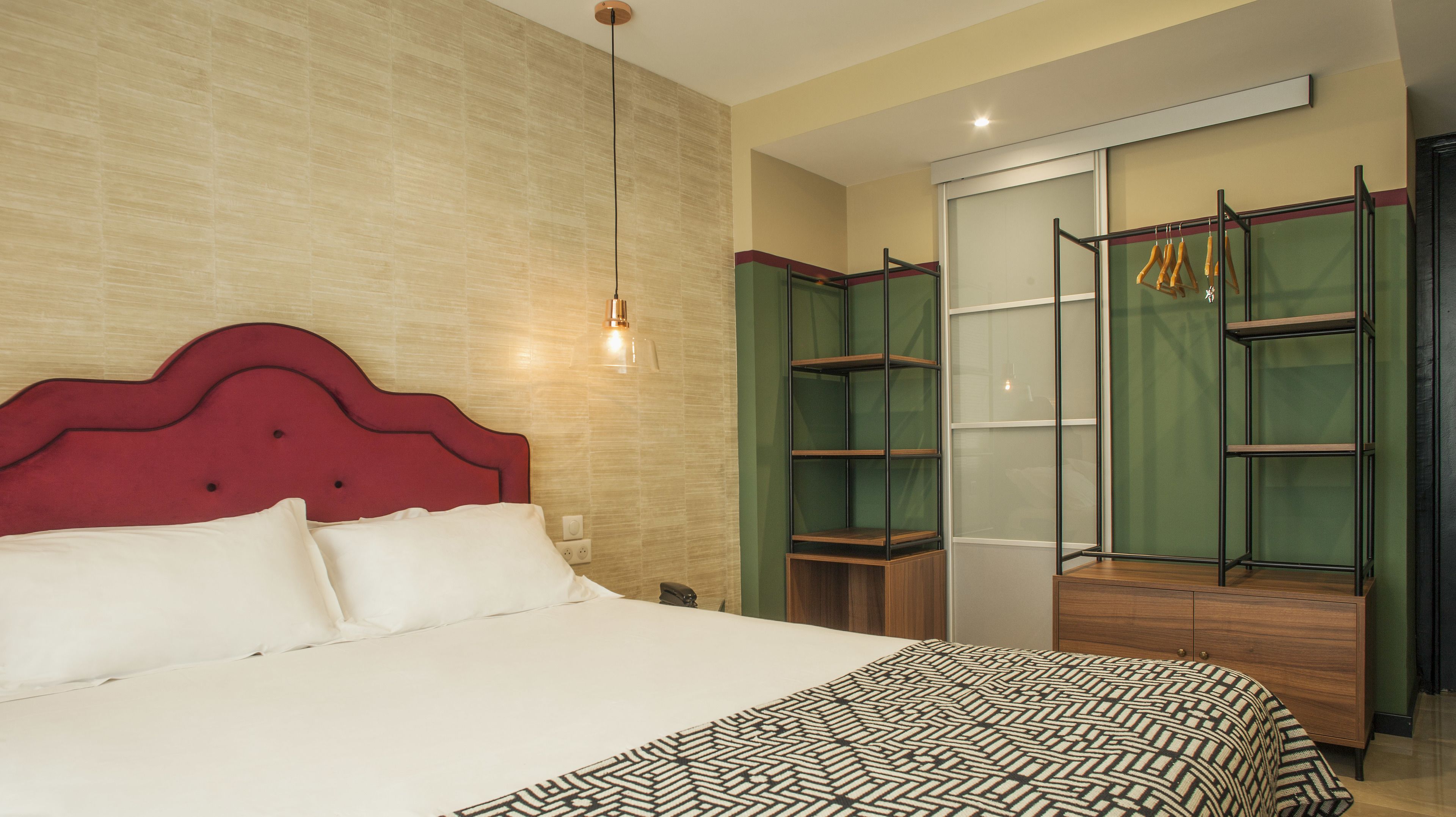 A hotel room with a large bed, a wardrobe with a mirror, and a hanging rack.