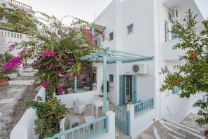 A white building with a balcony, potted plants, and a staircase. - Aphrodite Studios (Astypalaia)