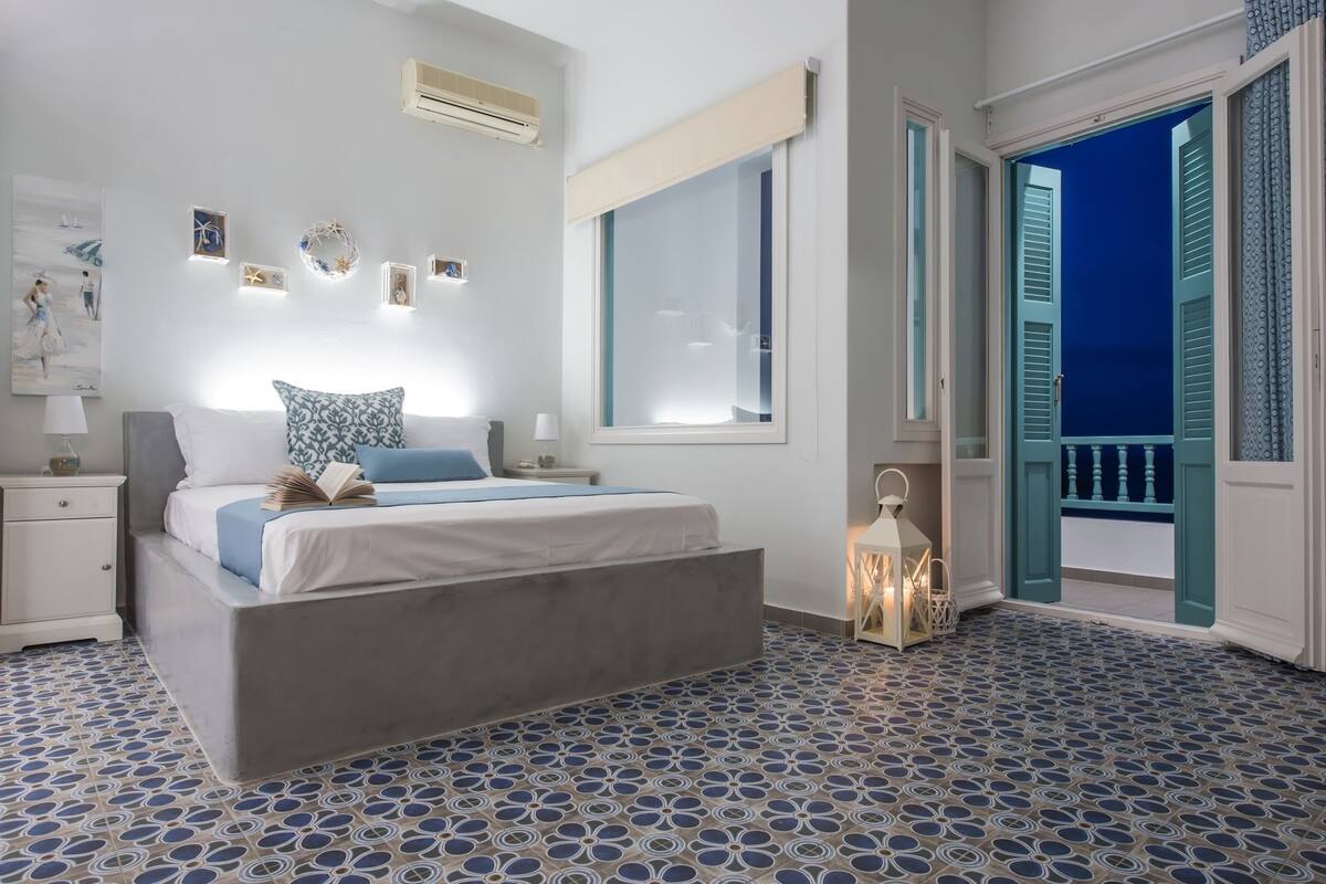 A bedroom with a bed, bedside table, wall art, and a window.