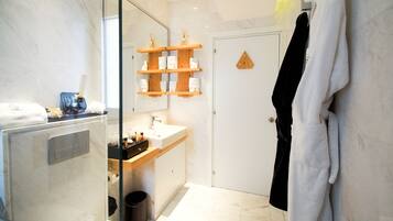 A modern bathroom with a glass shower enclosure, a wooden vanity, and a towel rack.
