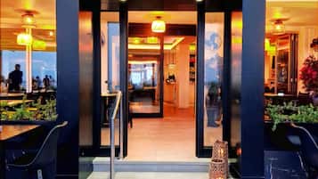 The entrance to Enigma Restobar with a modern design, featuring a glass door, outdoor seating area, and a visible interior with tables and chairs.