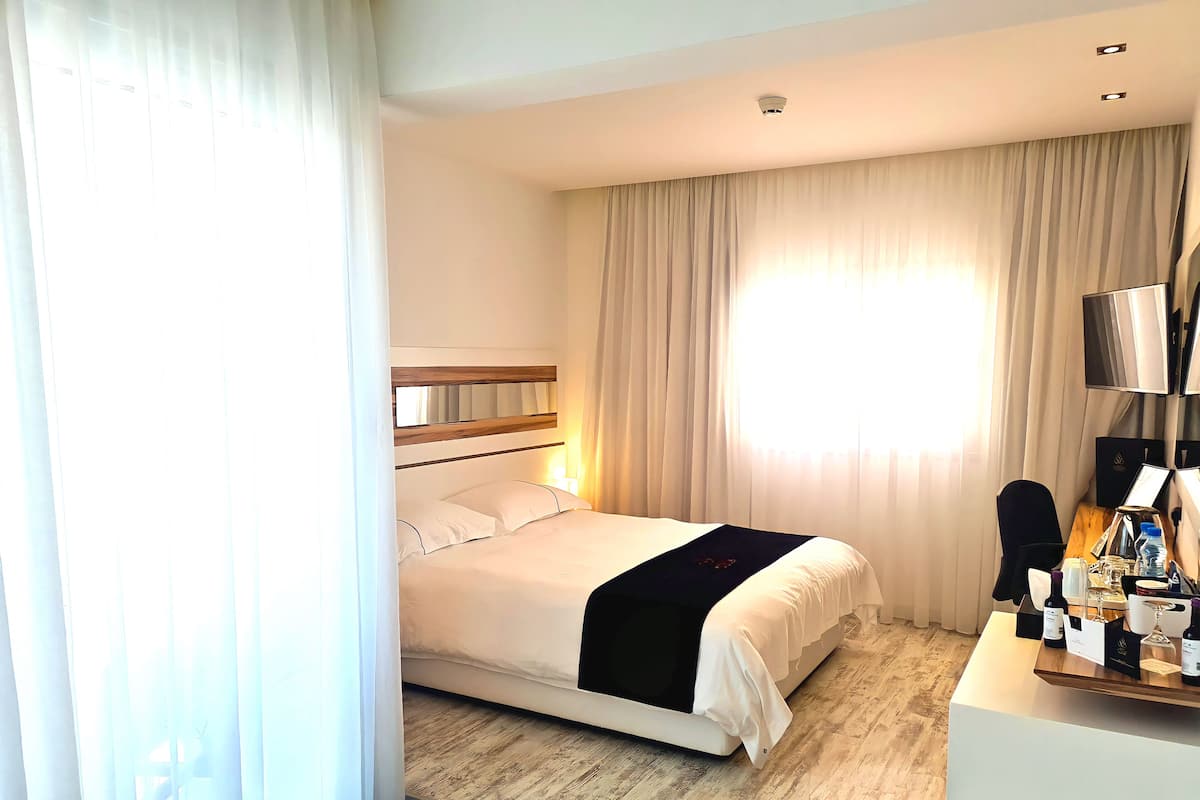 Une chambre d’hôtel avec un lit, un bureau équipé d’un ordinateur et une fenêtre avec des rideaux.