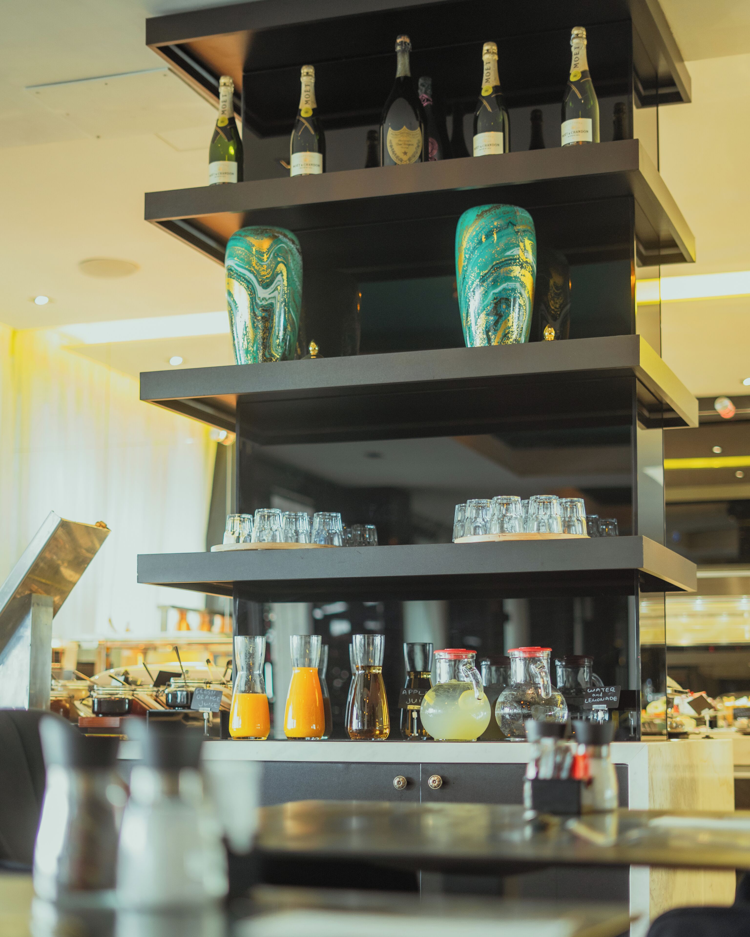 A multi-tiered display of various bottles and glasses, likely for beverages, in a well-lit indoor setting.