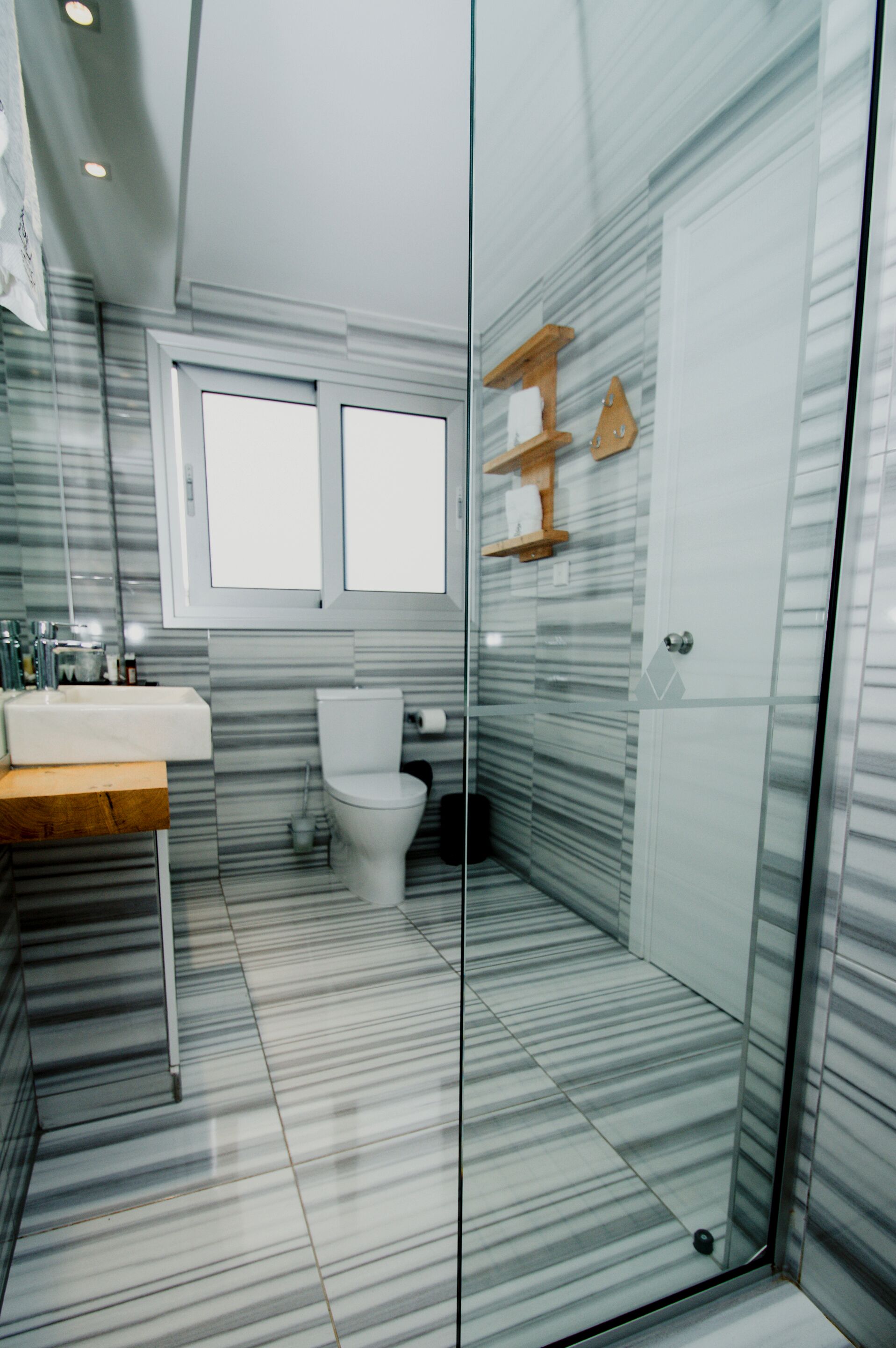 A modern bathroom with a glass shower enclosure, a toilet, and a vanity with a sink.