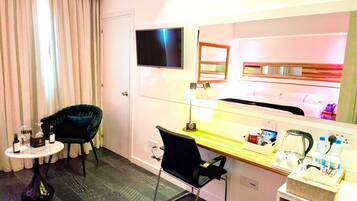 Une chambre d’hôtel équipée d’un bureau, d’une chaise, d’une télévision et d’un mini-bar.
