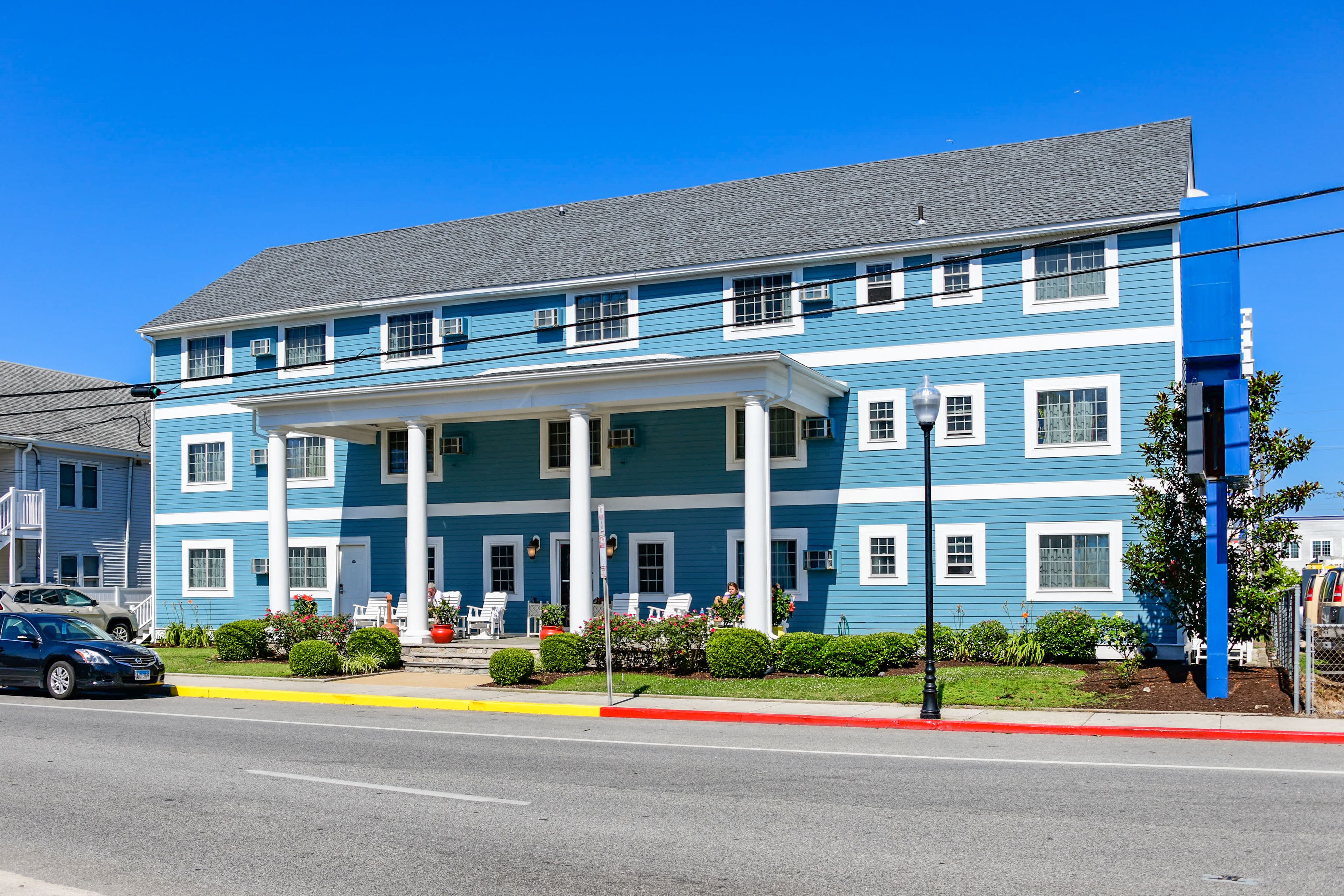 A two-story building with a blue facade, white trim, and a covered porch.