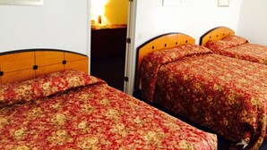 A room with three beds, each with a floral-patterned bedspread, a wooden headboard, and a ceiling fan. - Stardust Motel and Suites El Dorado KS (El Dorado)