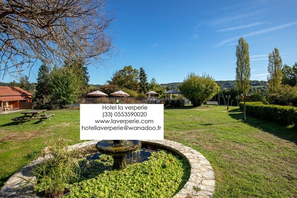 A hotel with a garden, a fountain, and picnic tables. - Hôtel La Verperie (Sarlat-la-Canéda)