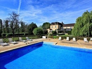 A swimming pool with lounge chairs and a house in the background.
