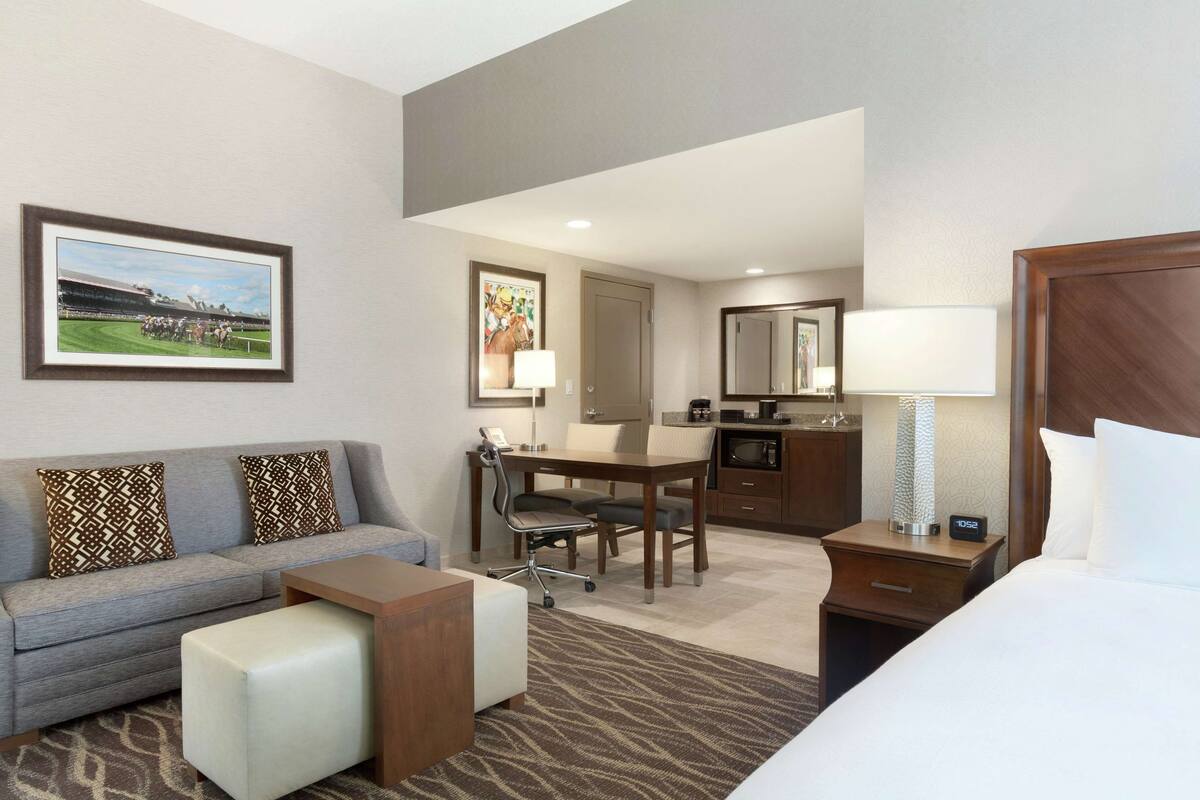 Ein Hotelzimmer mit Sofa, Schreibtisch, Bett und einer Küchenzeile.