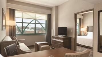 A hotel room with a large window, a TV, a bed, a desk, and a chair.
