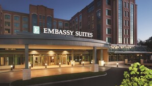 Un hôtel reconnaissable à son grand panneau « Embassy Suites », à son entrée abritée et à sa façade bien éclairée.