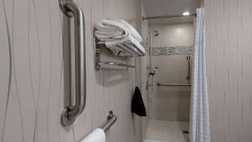 Ein Badezimmer mit Dusche, Haltegriffen und Handtuchhalter.