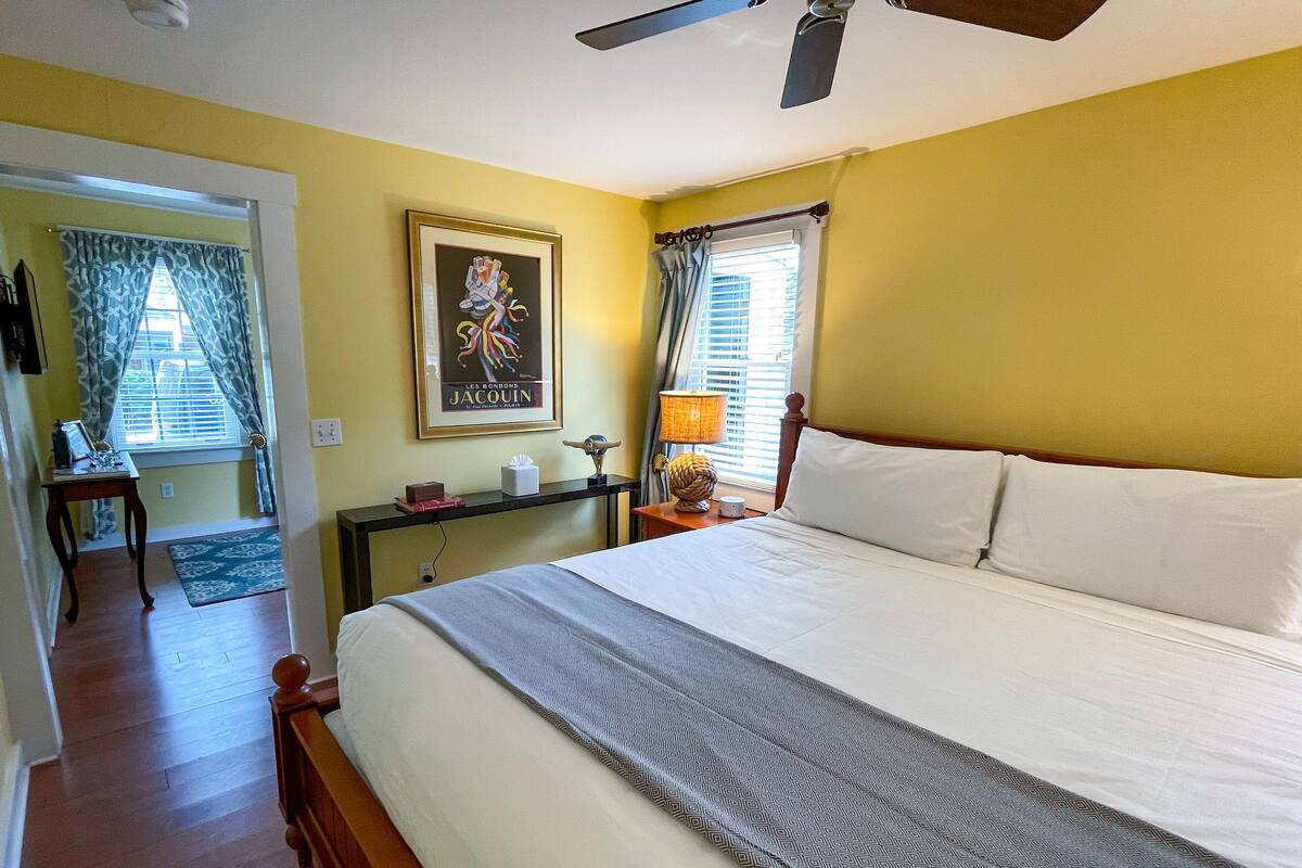A hotel room with a bed, bedside table, lamp, and a painting on the wall.