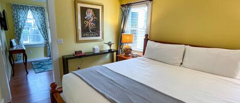 A hotel room with a bed, bedside table, lamp, and a painting on the wall.