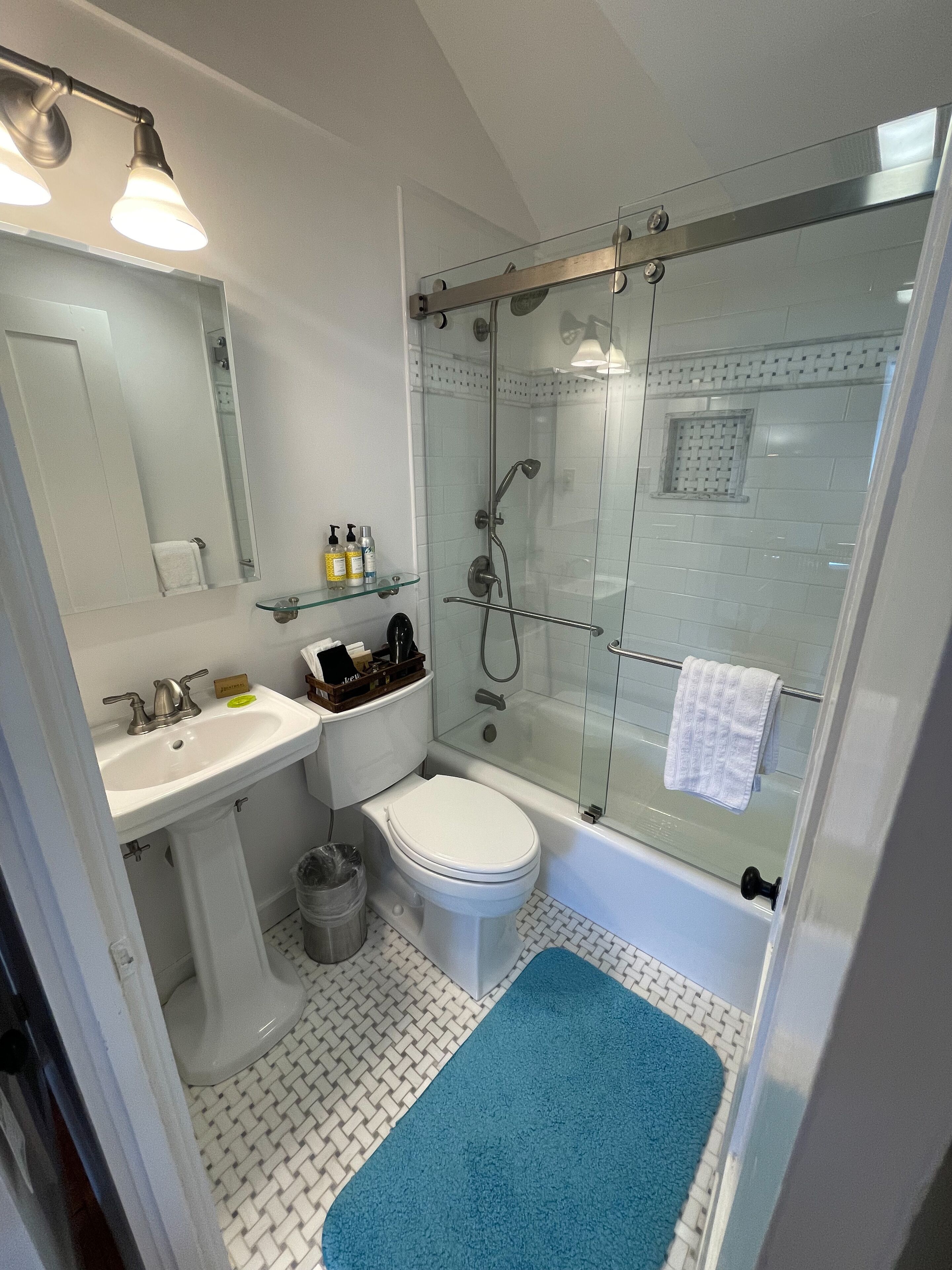 A modern bathroom with a glass-enclosed shower, a white sink, and a toilet.