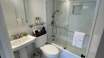 A modern bathroom with a glass-enclosed shower, a white sink, and a toilet.
