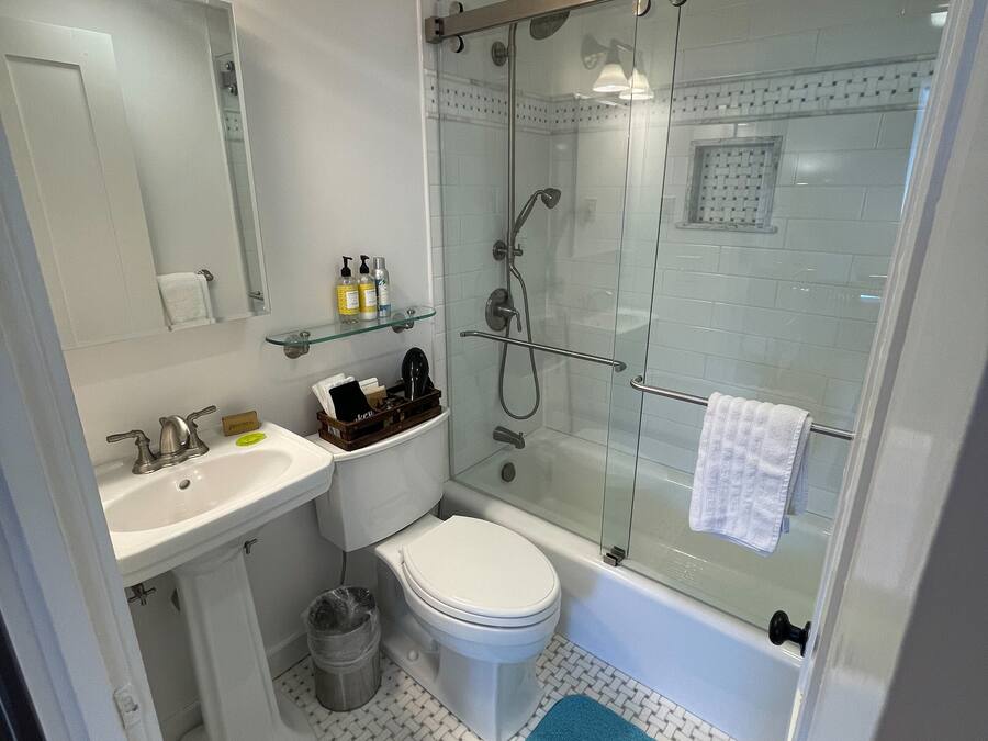 A modern bathroom with a glass-enclosed shower, a white sink, and a toilet.