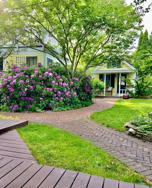 Ein Gartenweg führt zu einem Haus mit einer Veranda.
