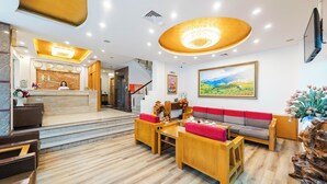 Vestíbulo de hotel con recepción, zona de estar, escalera y obras de arte.