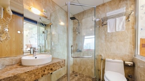 Un baño moderno con ducha envuelta en vidrio, un lavamanos blanco y un inodoro.