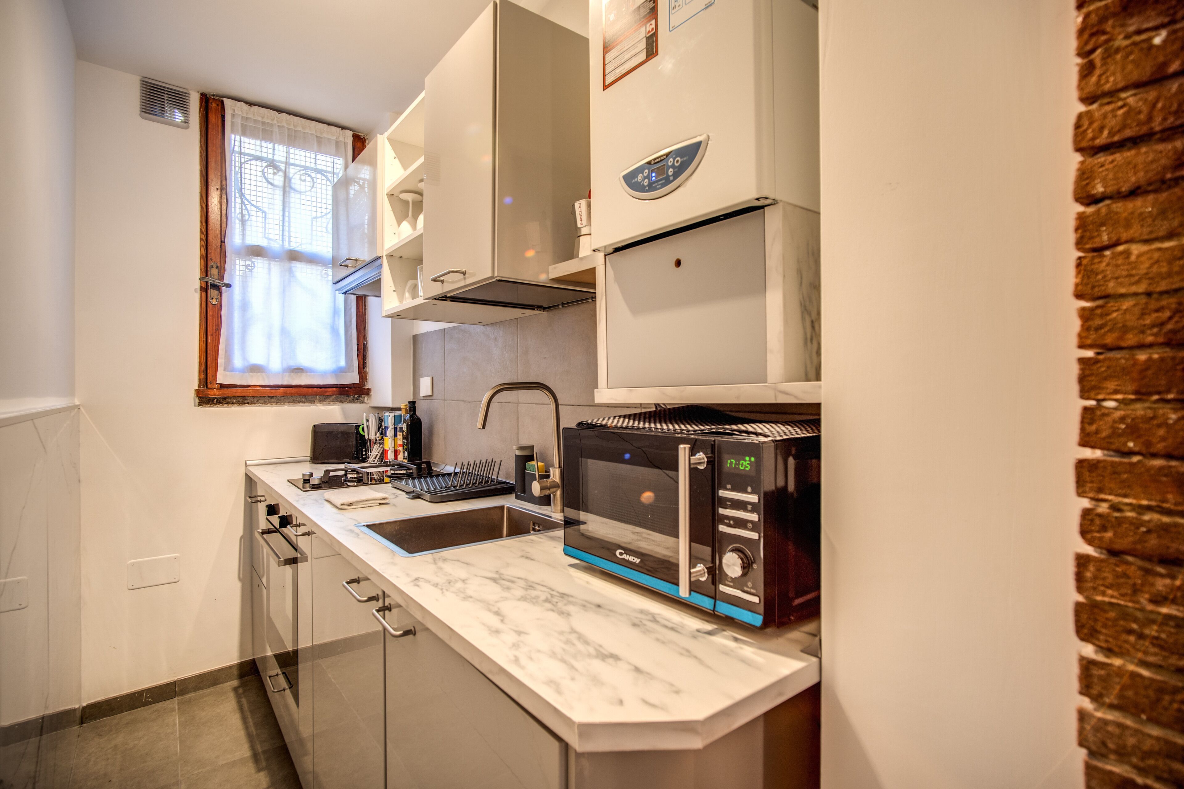 Cozinha compacta com micro-ondas embutido, torradeira e pia.