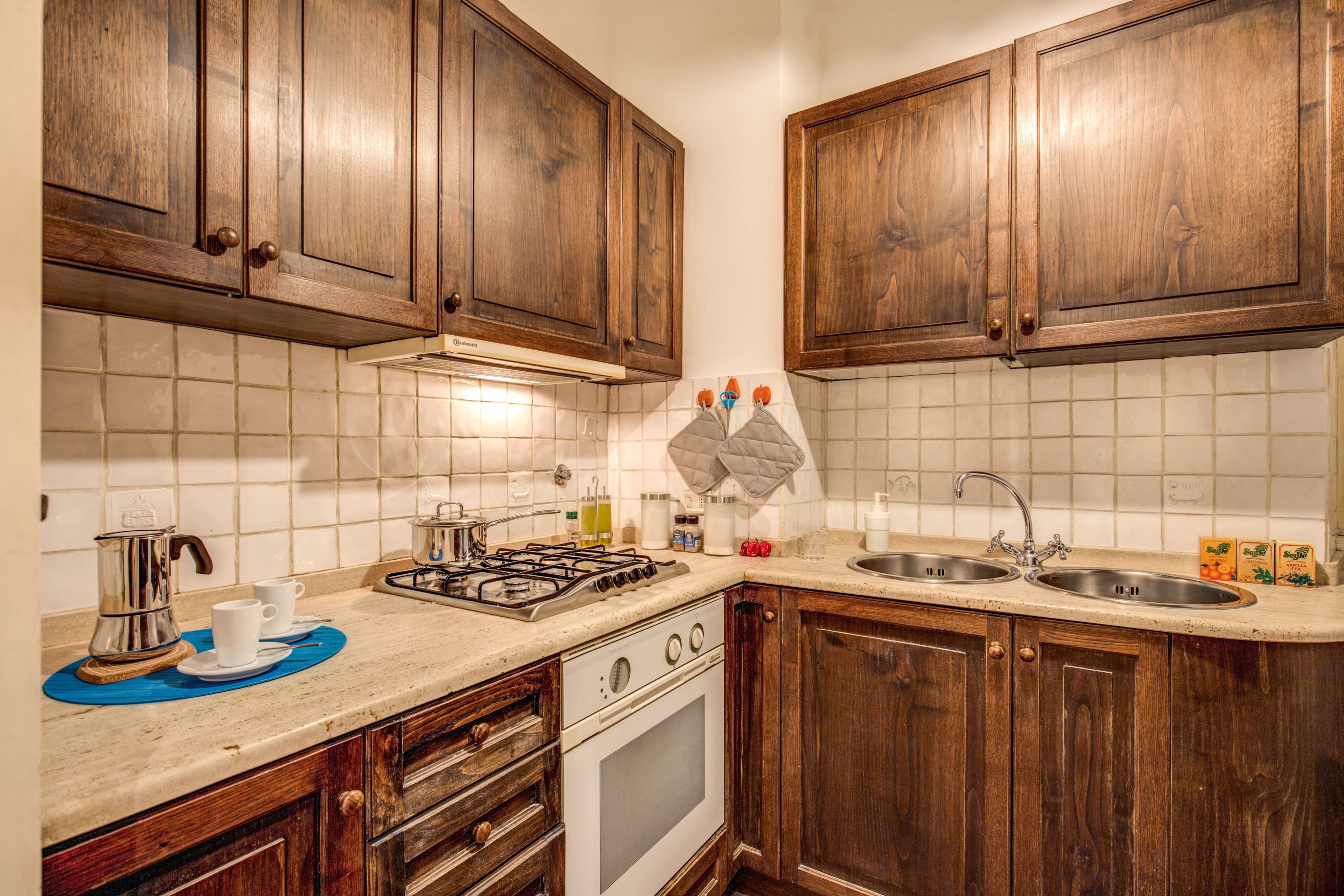A kitchen with wooden cabinets, a stove, a sink, and a countertop with various items.