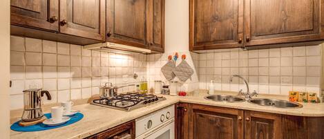 Una cocina con armarios de madera, una estufa, un fregadero y una encimera con varios objetos.