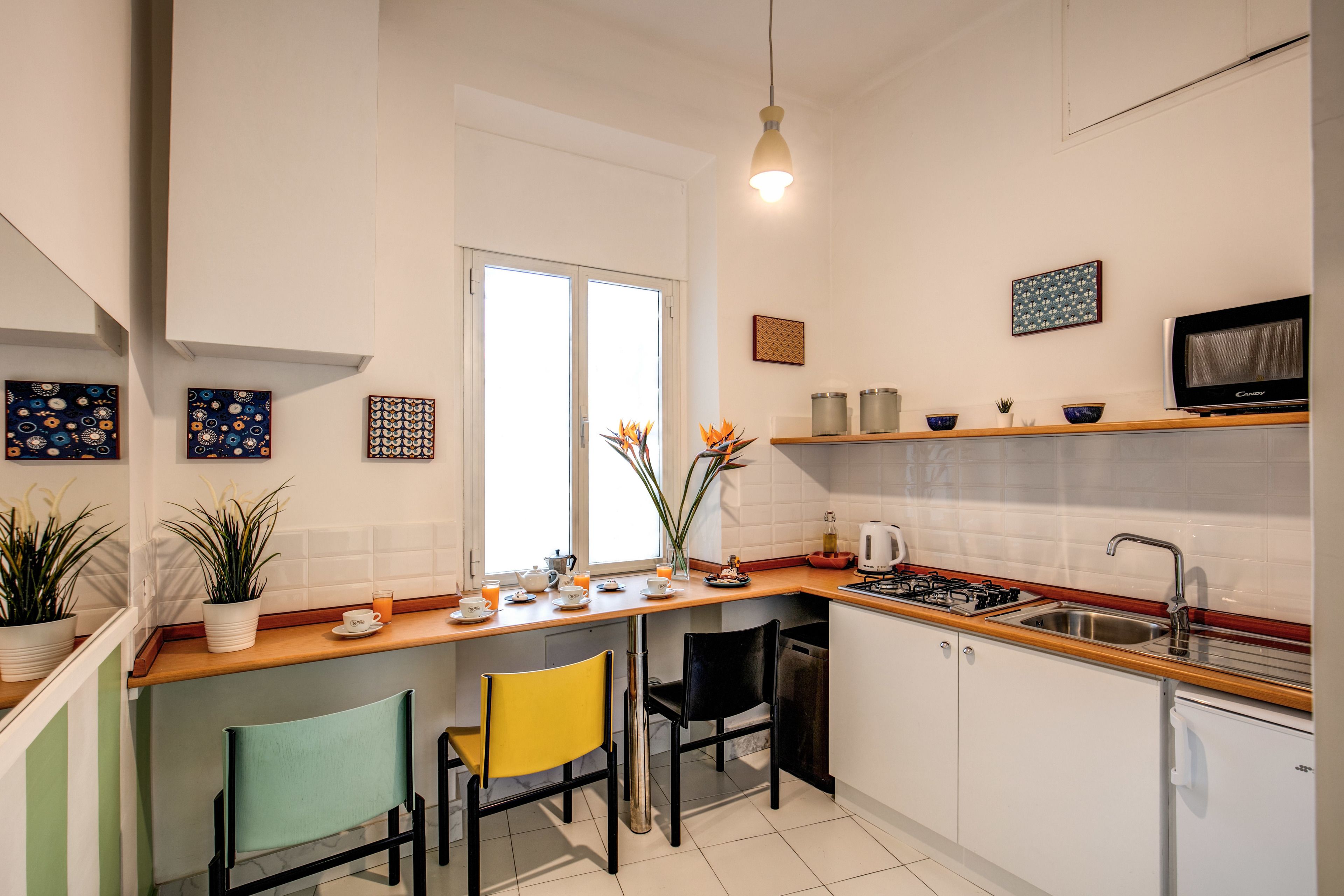Eine moderne Küche mit Holzarbeitsplatte, zwei Stühlen, einer Spüle, einem Herd und einem Kühlschrank.