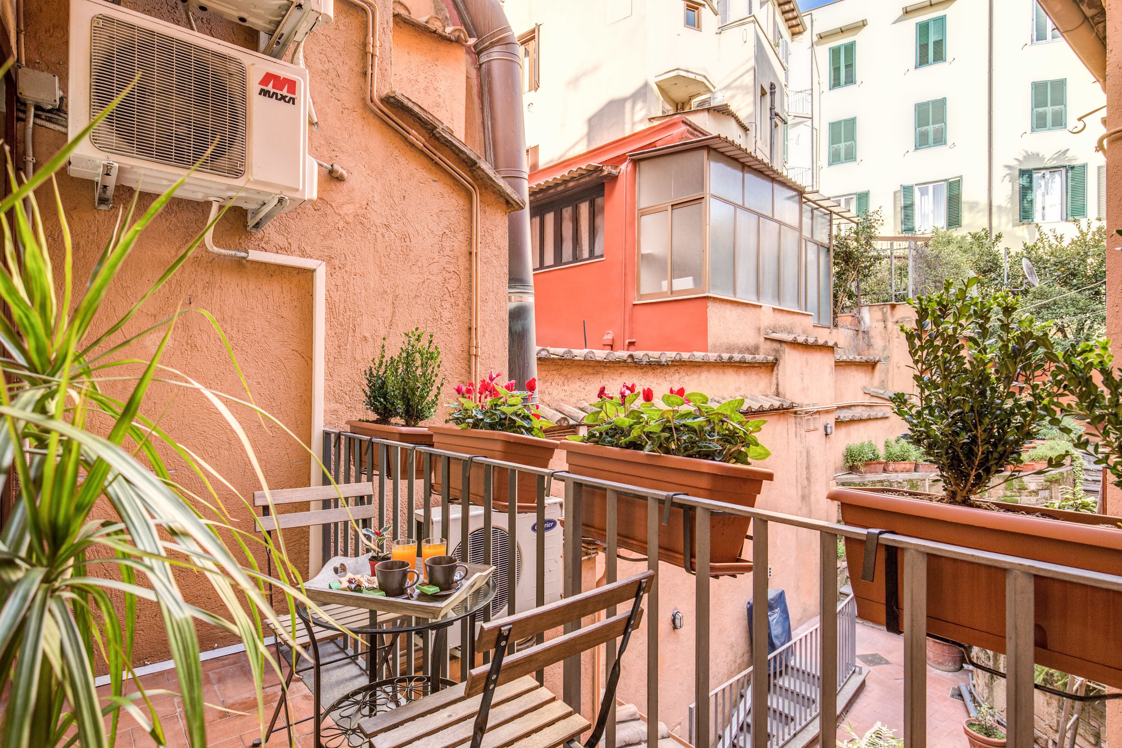 Un balcon avec une table, des chaises et des plantes en pot.